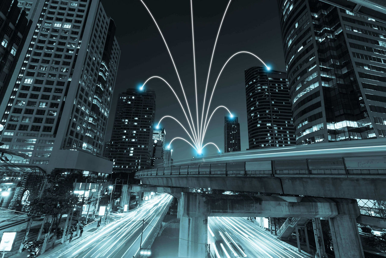 ライトアップされた高層ビルと明るい光の軌跡が広がる夜の街並み