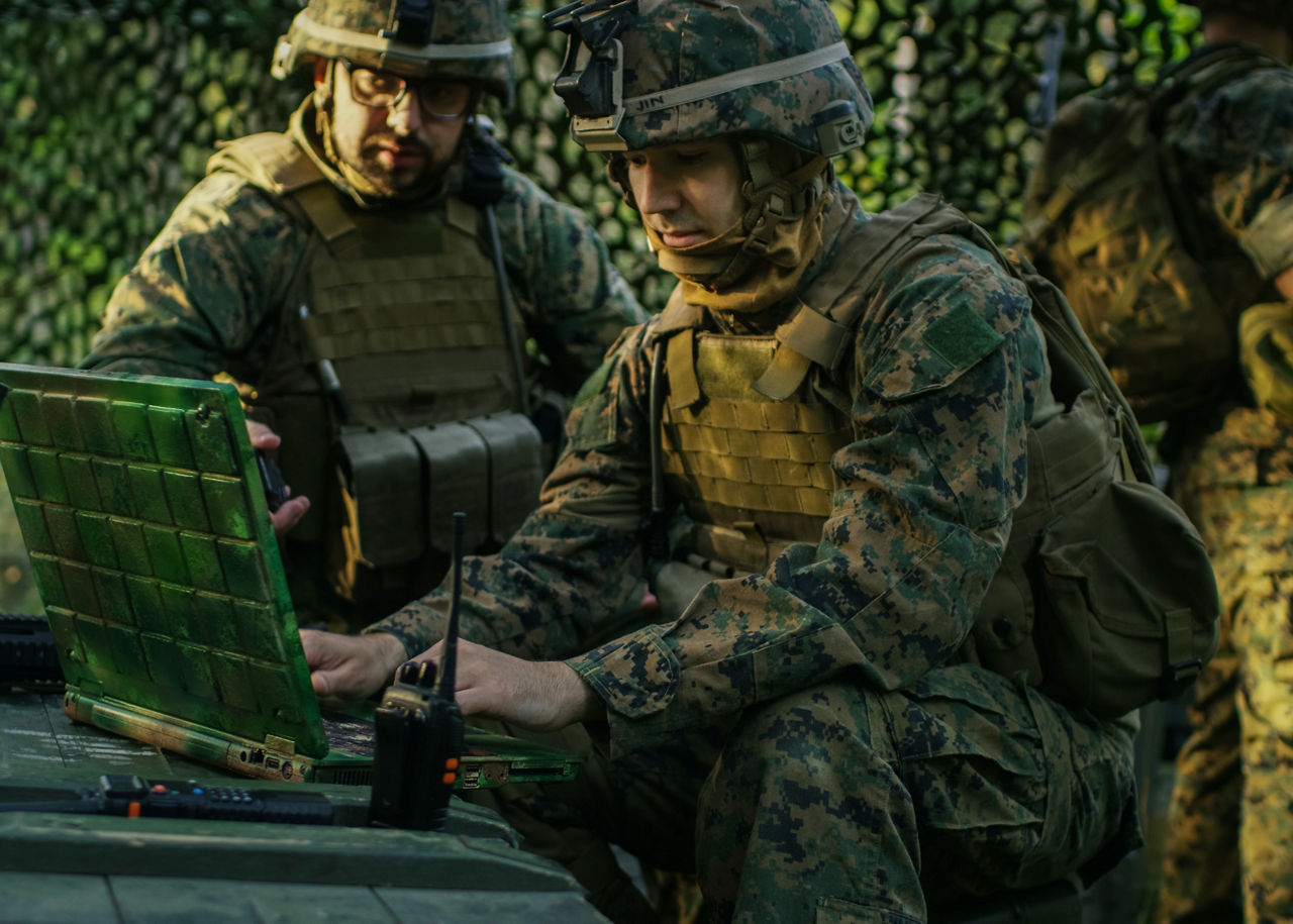 Military Staging Base, Officer Gives Orders to Chief Engineer, They Use Radio and Army Grade Laptop. They're in Camouflaged Tent in a Forest. They're on Reconnaissance Operation/ Mission.