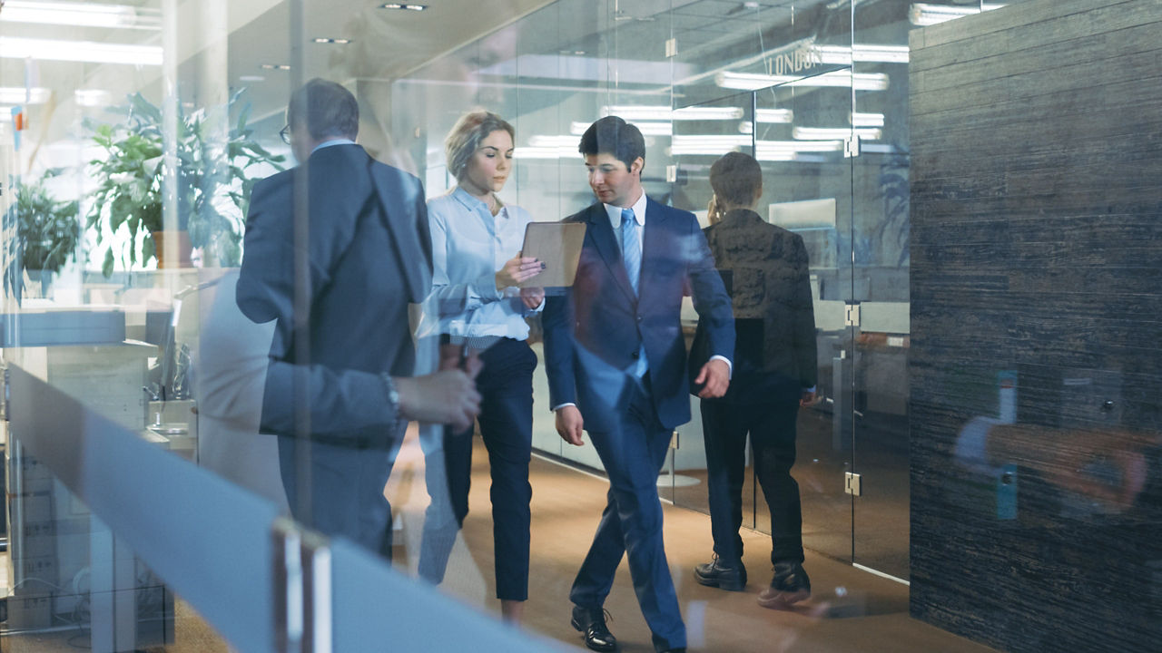 Two people walking in an office hallway holding papers and discussing their data center security.