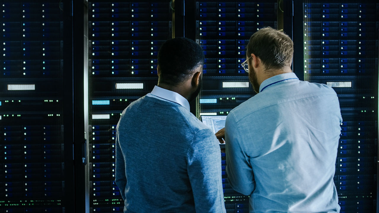 Dos profesionales de redes trabajando en un salón de centro de datos oscuro con luces led