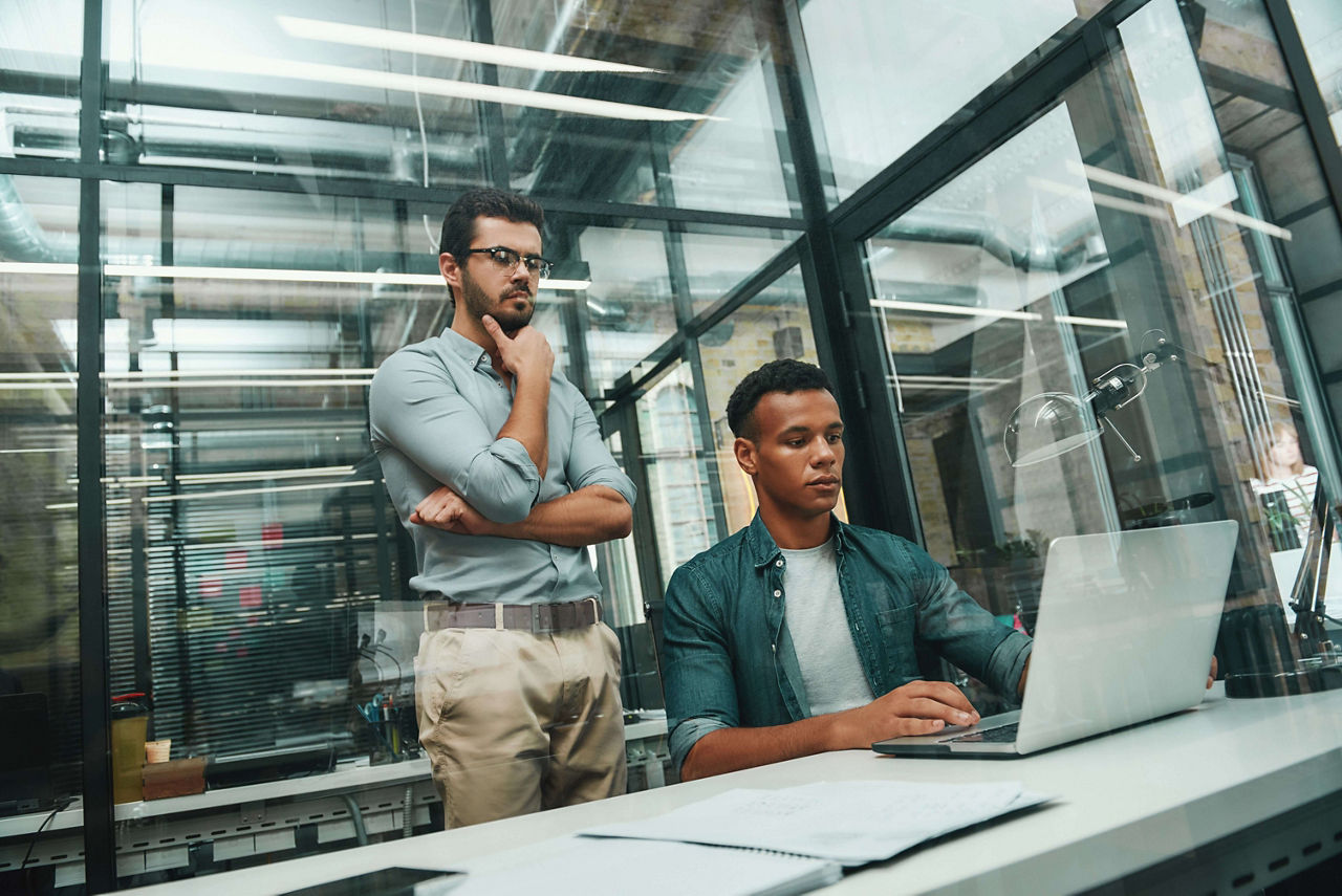 オフィスのラップトップでジュニパーの次世代ファイアウォールサービスを利用している2人のソフトウェアエンジニア。