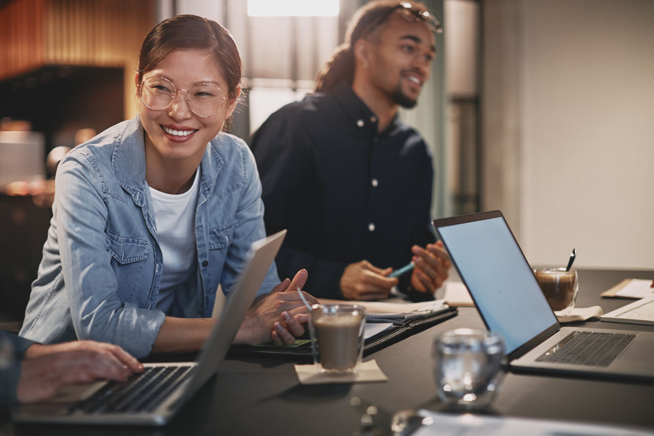 Diverse businesspeople smiling while working with colleagues in