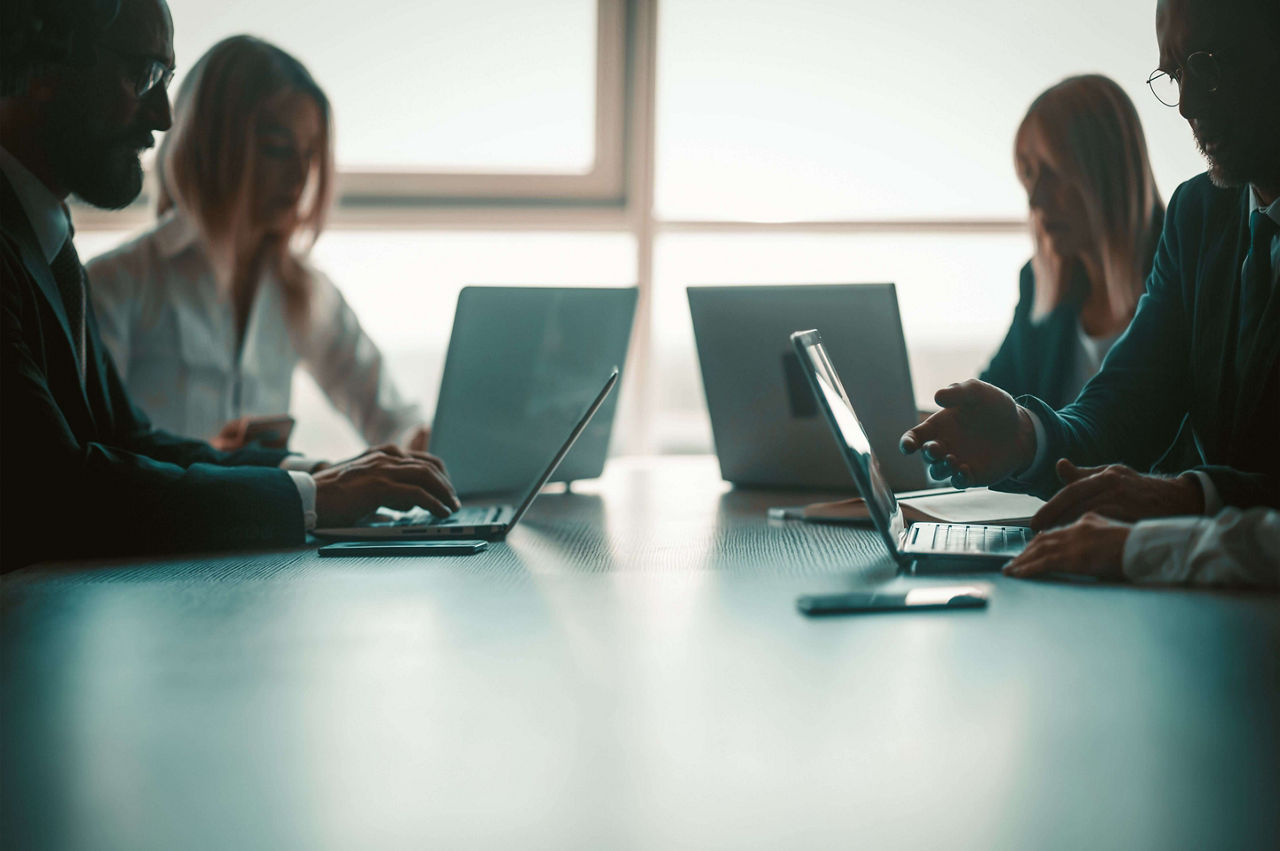 Four people using their laptops to do research on zero trust security for networks.