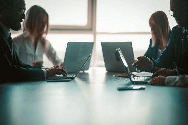 Four people using their laptops to do research on zero trust security for networks.