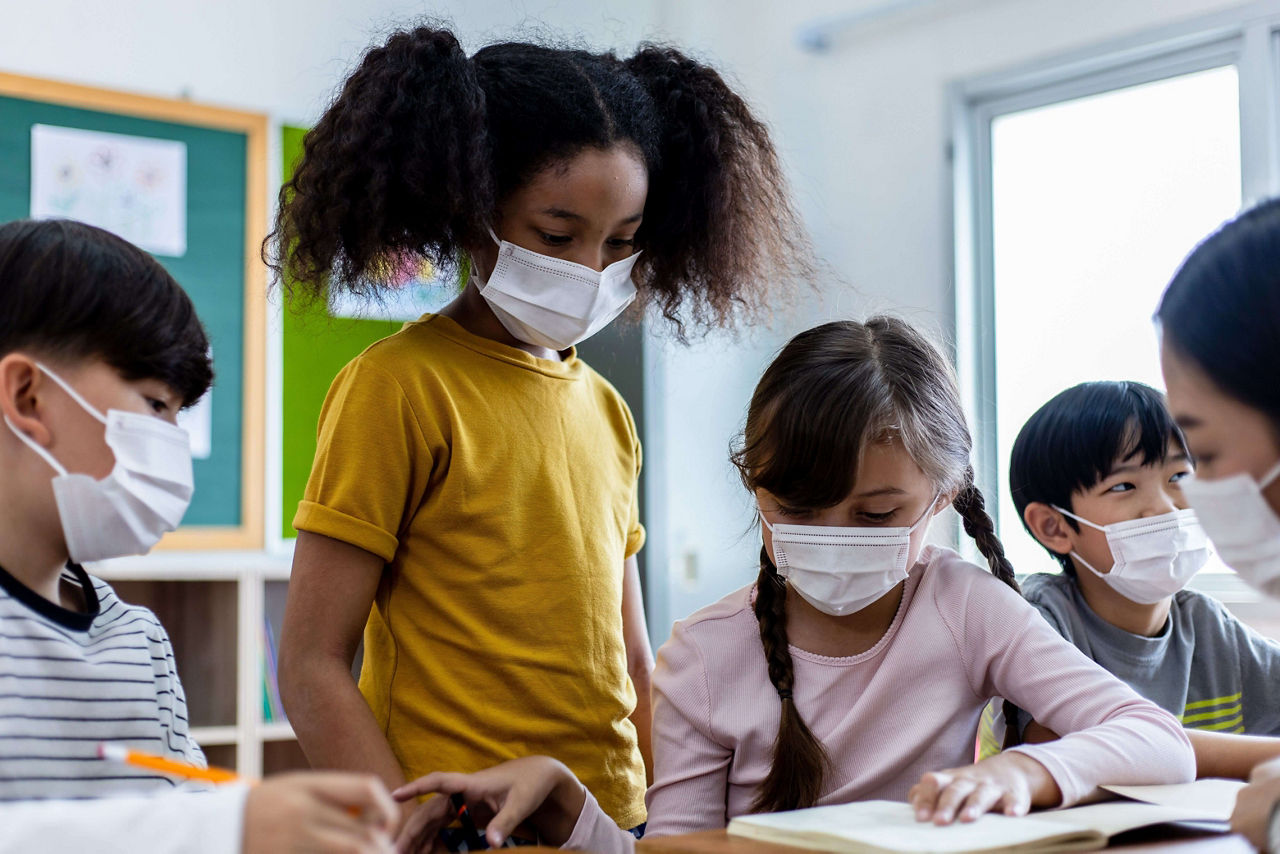 Diversity of children students wearing medical masks in the classroom.