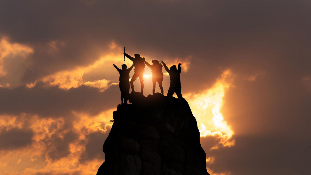 一群人站在山顶，阳光透过云彩洒下来