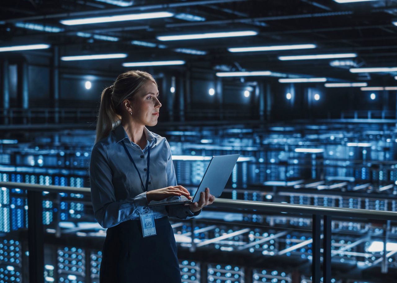 Data Center Female It Specialist Using Laptop. Server Farm Cloud Computing and Cyber Security Maintenance Administrator Working on Computer. Information Technology Professional.