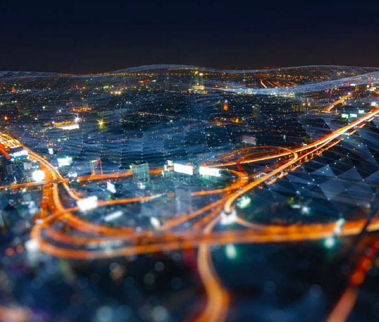 未来的な都市の夜景の中を走る、明るいオレンジ色の光で輝く高速道路のネットワーク