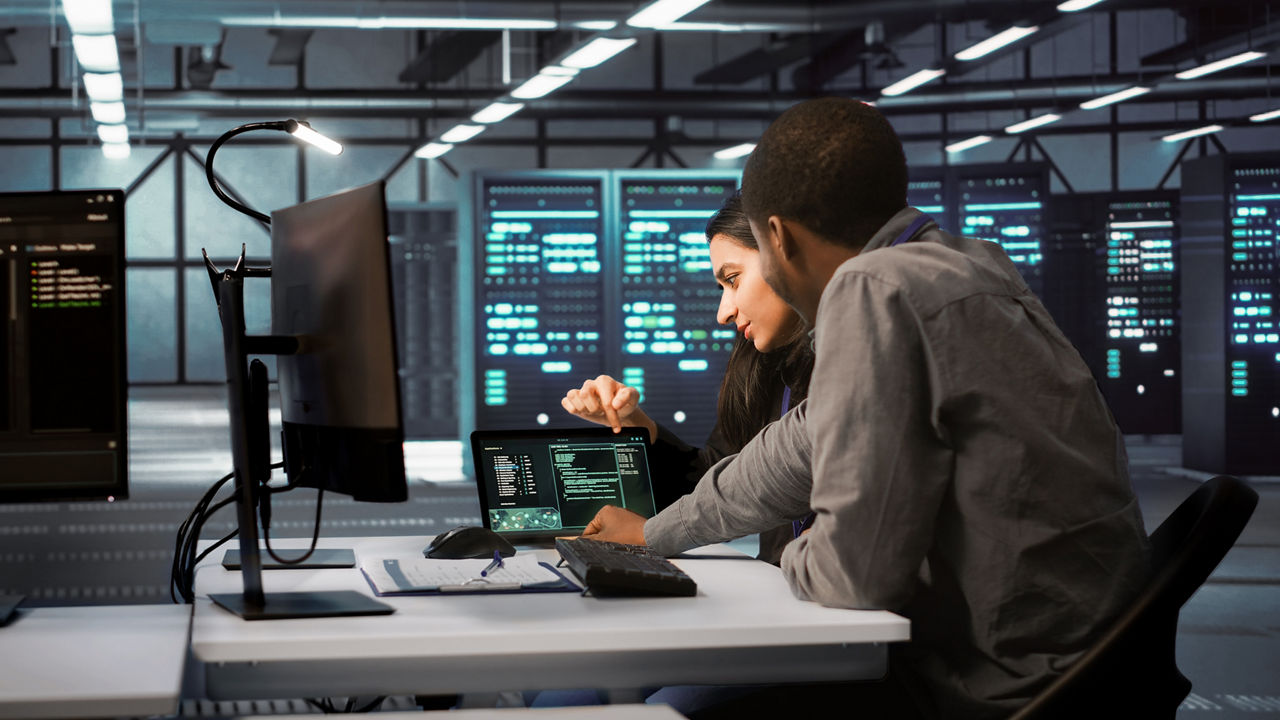 Diverse team of engineers looking at parameters in data center on tablet